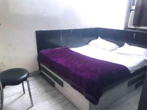 a bed with a purple blanket and a chair in a room at Hotel Mahi in Jaipur