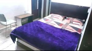 a bedroom with a purple bed and a chair at Hotel Mahi in Jaipur