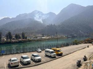 a group of cars parked on a road next to a river at Skyline Hotel in Uttarkāshi +5 photos