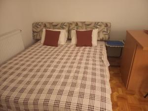 a bed with a plaid blanket and two pillows at Prelep mali stan sa terasom in Petrovaradin