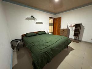 a bedroom with a green bed and a window at Taibessi in Dili
