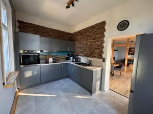 a kitchen with gray cabinets and a brick wall at Canossa Lodge in Bad Harzburg +3 photos