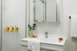 a white bathroom with a sink and a mirror at Bakan- Quartier des Congres, Convention District in Montreal
