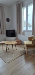 a living room with two tables and a tv at Appartement coquet proche plage in Berck-sur-Mer