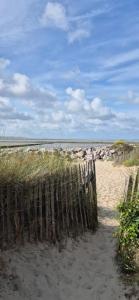 a wooden fence on a beach with rocks and the ocean at Appartement coquet proche plage in Berck-sur-Mer