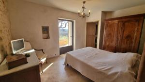 a bedroom with a bed and a tv and a window at La Fabrique in Gargas