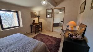a bedroom with a bed and a desk with a lamp at La Fabrique in Gargas