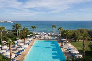 ein Bild von einem Pool mit Sonnenschirmen und dem Meer in der Unterkunft Hotel Del Levante in Torre Canne