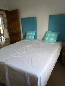 a large white bed with blue pillows on it at Residence Poolside Haven in Grande Gaube