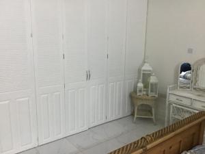 a room with white doors and a bed and a table at chill spot on the green in Belmont