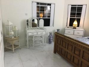 a bedroom with white furniture and a mirror at chill spot on the green in Belmont