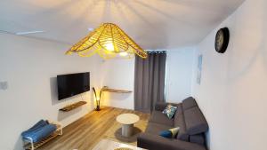 a living room with a couch and a tv at Pépite citadine à St Pierre in Saint-Pierre