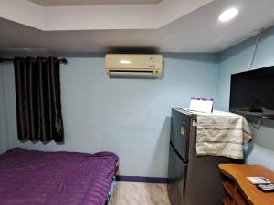 a small room with a bed and a refrigerator at บ้านสายรุ้ง กระทุ่มแบน in Samut Sakhon