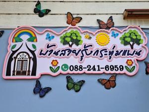 a sign on the side of a building with butterflies at บ้านสายรุ้ง กระทุ่มแบน in Samut Sakhon