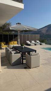 a patio with a table and chairs and an umbrella at Villa Loggia in Ferendináta