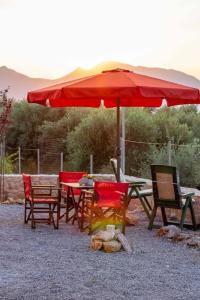 ein Tisch und Stühle mit einem roten Sonnenschirm in der Unterkunft Ckamares in Sikéa