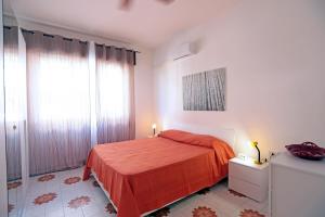 a white bedroom with a red bed and a window at Argo apartment, fronte mare, kaucana beach in Villaggio Azzurro