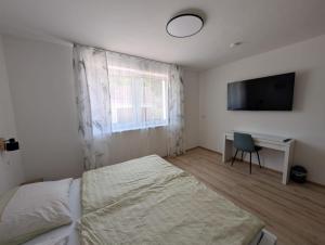 a bedroom with a bed and a desk and a television at Wagramzimmer - Satzingerhof in Großwiesendorf +3 photos