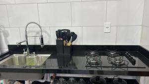 a kitchen counter with a stove and a sink at Residencial Ebenezer conforto perto da ufac in Rio Branco