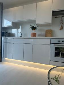a white kitchen with white cabinets and a table at Ocean Drive Boutique Apartment with use of Day time Beach Hut in Brean +34 photos