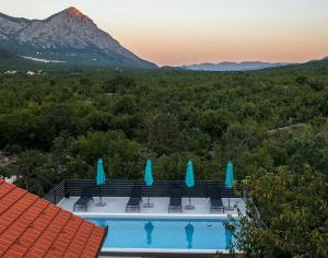 a pool with chairs and umbrellas and a mountain at Villa Ika in Gomila
