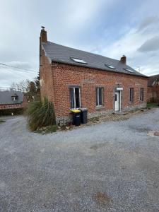 a brick building with two windows and two trash cans at Maison de village in Mecquignies