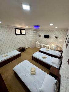a room with three beds and a tv on the wall at Imran Guest House in Samarkand