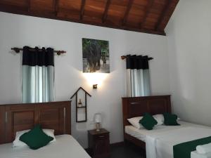 two beds in a room with green and white at Seeing Green Udawalawa in Udawalawe