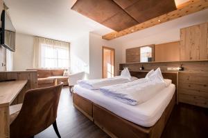 a bedroom with a bed and a desk and a table at Hotel Waldheim in Valle Di Casies +89 photos