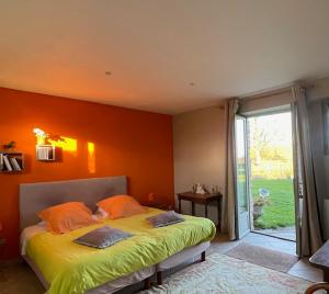 a bedroom with a bed with an orange wall at Grand Mainguet in Saint-Lambert-la-Potherie