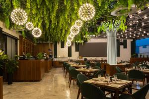 a restaurant with tables and chairs and plants at Grand Dior in Tashkent