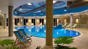 a large pool in a hotel with chairs and tables at Domki Aleja Róż in Międzyzdroje