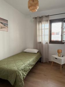 a bedroom with a green bed and a window at El Puertito Beach Retreat in Agaete