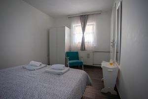 a bedroom with a bed and a chair and a window at Apartman Marija in Bošnjaci