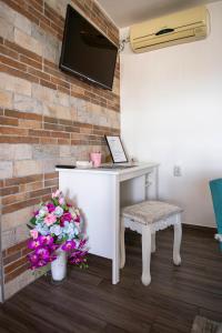 a white desk with a chair and flowers next to a brick wall at Apartman Marija in Bošnjaci
