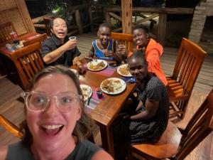 a group of people sitting around a table eating food at Sunscape lodge in Fort Portal