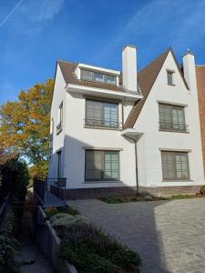 a large white house with a roof at Gastenverblijf Onder een Oude Eik in Tongeren +20 photos