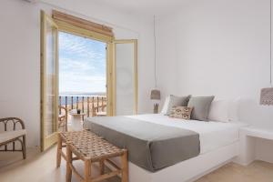 a white bedroom with a large bed and a balcony at Kastella Sunset Villa Three in Kithnos