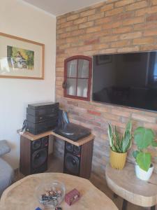 a living room with a tv and a brick wall at Apartament Lipowa in Lidzbark