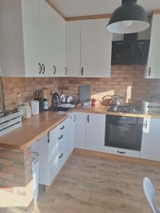 a kitchen with white cabinets and a wooden counter top at Apartament Lipowa in Lidzbark +3 photos