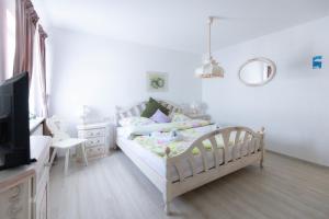 a white bedroom with a bed and a tv at Landhaus Süchterscheid in Süchterscheid