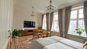 a bedroom with a bed and a tv and some windows at Old Town Gdansk Olives Marina Apt 2 min walk to Motlawa River in Gdańsk