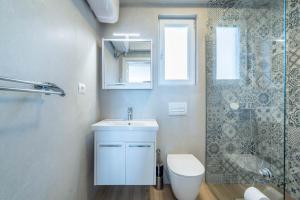 a bathroom with a toilet and a sink and a shower at Blue Eye Apartment in Sarandë +29 photos