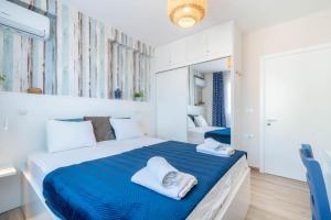 a white bedroom with a blue bed with towels on it at Blue Eye Apartment in Sarandë