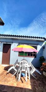 a patio with two chairs and an umbrella at Kitnet da Elô in Tramandaí +18 photos