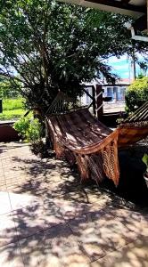 a hammock sitting under a tree on a patio at Kitnet da Elô in Tramandaí