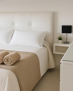 a white bedroom with a white bed with towels on it at Terraza Marina V in Pinamar