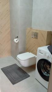 a bathroom with a toilet and a washing machine at Apartament Skarbowa East in Leszno