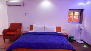 a bedroom with a bed and a red chair at SunRise Beach Resort in Iberekodo