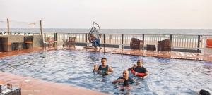 a group of men in a swimming pool near the ocean at SunRise Beach Resort in Iberekodo
